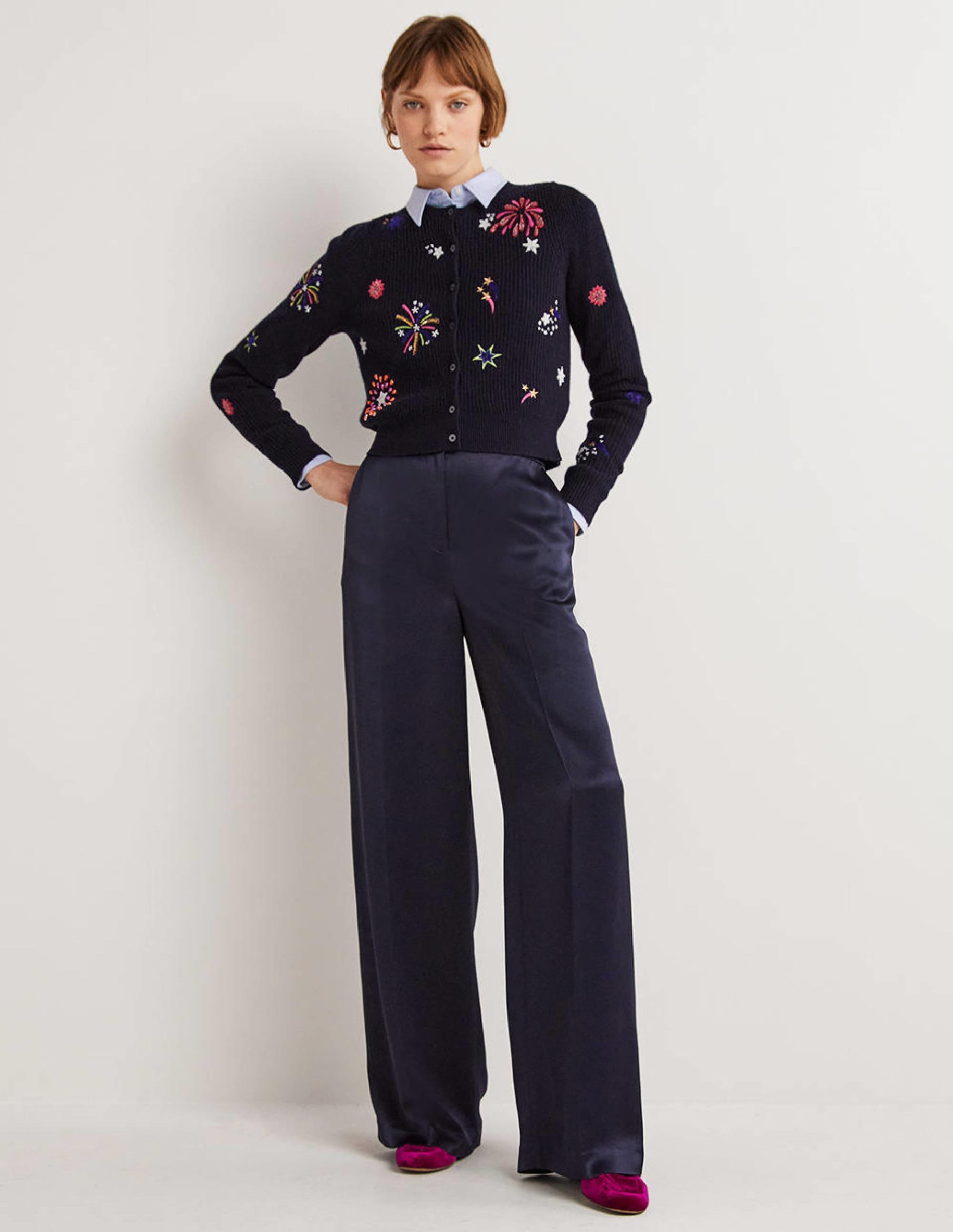 A pair of navy satin wide-leg trousers worn by a woman, high-waisted with a relaxed fit, made from shiny satin fabric.