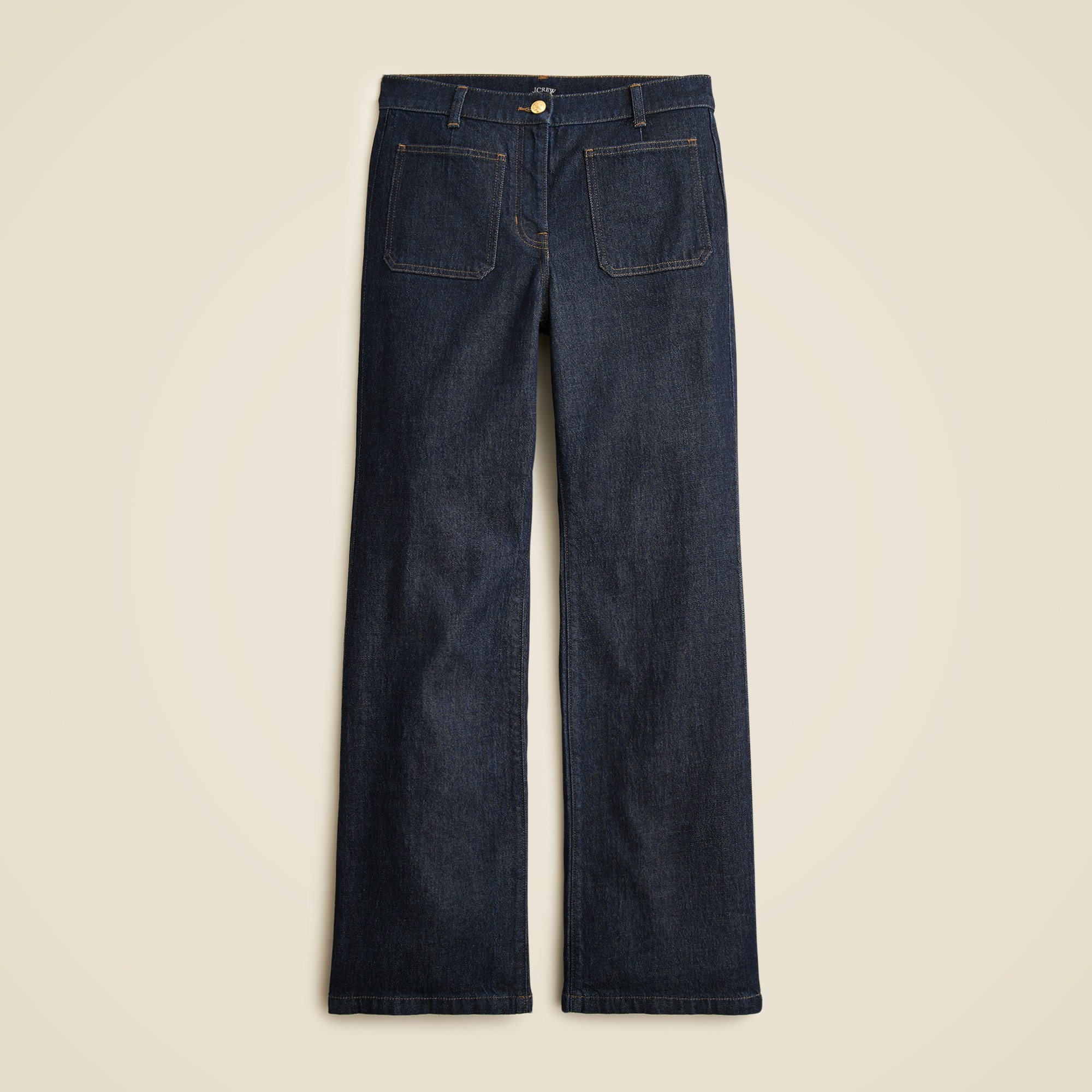 A pair of dark blue high-rise jeans with a kickout hem, patch pockets, and a zip fly.
