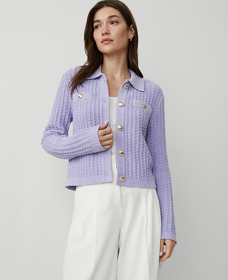 A woman wearing a lavender purple petite stitched collared sweater jacket with gold buttons, textured knit pattern, and faux chest pockets.
